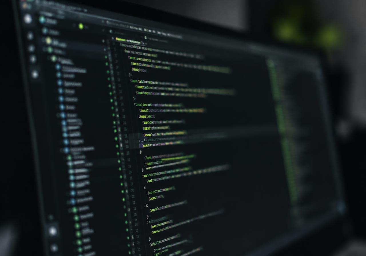 Code editor on a monitor with green syntax highlighting in a dark room